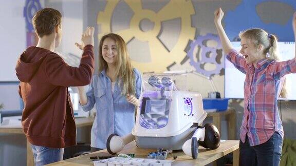 两个女孩和一个男孩打开全功能编程机器人与明亮的LED灯为学校科学课项目