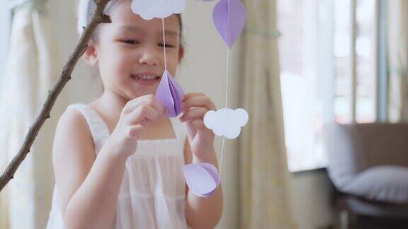 亚洲女孩帮助她的父母用花环装饰房间挂在树枝上复活节假期