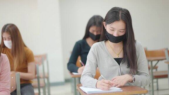 一群女学生戴着面具坐在大学教室里学习和考试这是新常态
