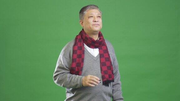 穿着灰色毛衣和红围巾的亚洲老人