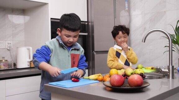 两个小男孩在厨房里切水果
