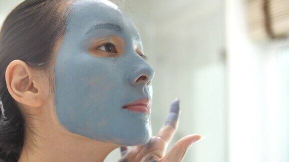 亚洲人在家里的浴室里敷上了一个蓝色保湿面膜
