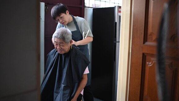 由于旅行禁令一位亚洲华人中年妇女正在厨房里为她的父亲修剪头发