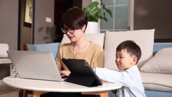 母亲在家工作儿子一起用平板电脑