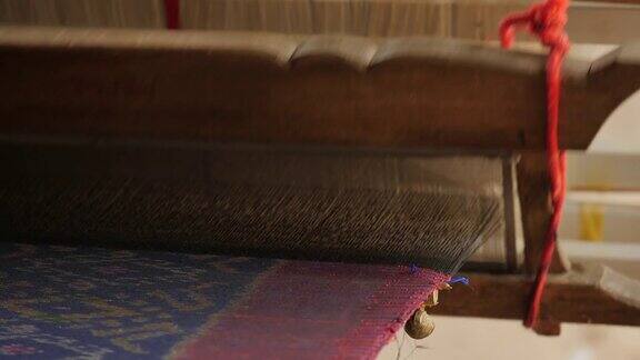传统纺织业在手工艺村妇女在木制织布机上工作纺纱制造丝绸或棉织品泰国的丝织