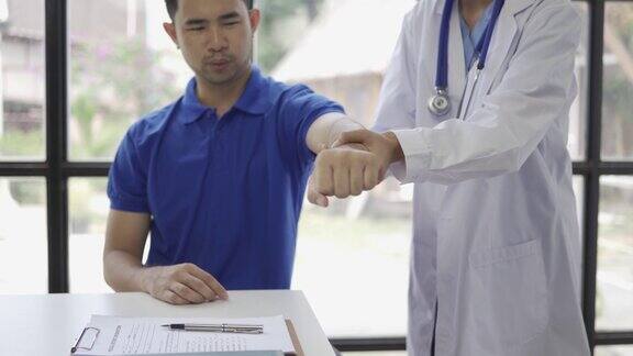 女医生为男病人进行举手理疗亚洲女理疗师在诊所工作帮助保护病人的手病人做伸展运动