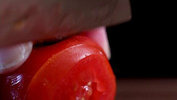 一位妇女用新鲜的樱桃番茄滴着水切成薄片
