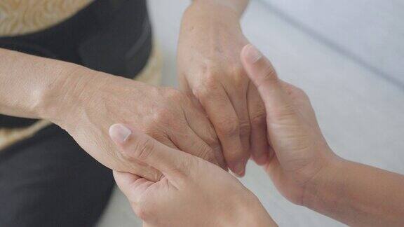 家庭护工手牵着手安慰亚洲老年妇女