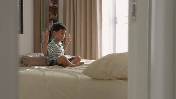 亚洲男孩在家卧室里练习冥想