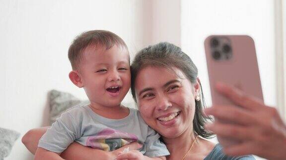 幸福家庭亚洲年轻妈妈和小儿子笑着给智能手机自拍视频家庭