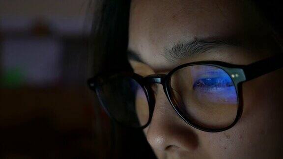 女人眼睛看着监视器在晚上上网