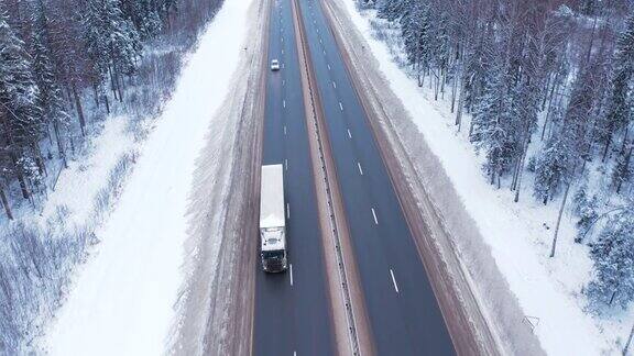 寒冷的冬天一辆白色卡车行驶在白雪覆盖的树林中