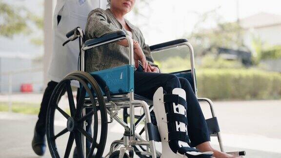 白人男医生带着坐在轮椅上的亚洲老年妇女到医院外休息的特写镜头