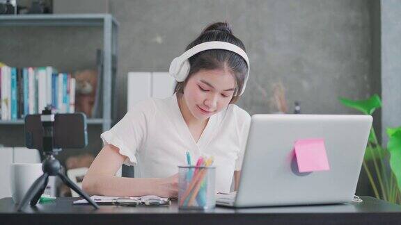快乐的亚洲女人用笔记本电脑在家学习在线课程