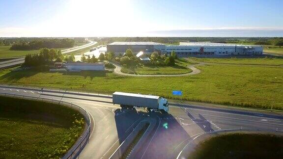 带货运拖车的白色半挂车通过高速公路立交桥鸟瞰图十八惠勒是新的装载仓库在背景中看到