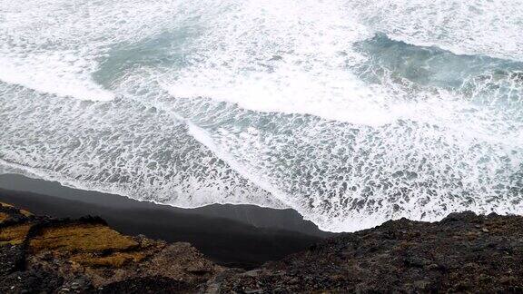 强大的海浪翻滚到岩石火山海岸线圣安涛岛徒步小径上的废弃黑沙滩佛得角从上面观看4K视频