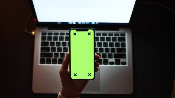 手持智能手机使用和显示绿色屏幕在夜间