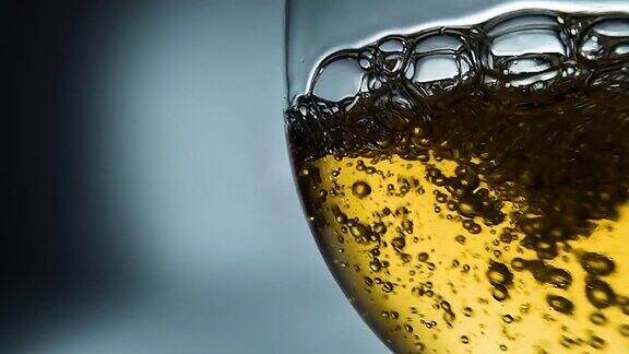 创意的4k微距慢动作视频白葡萄酒倒入杯子酒杯与倒白葡萄酒的特写与飞溅和气泡
