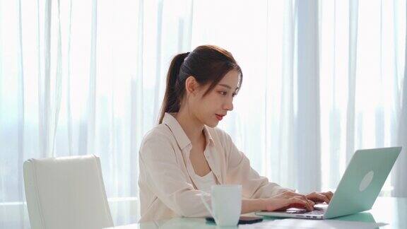 亚洲女商人使用科技笔记本电脑在线学习和工作在桌子上的房间