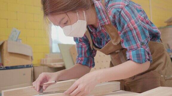 用铅笔和尺子在木板上工作的女木匠