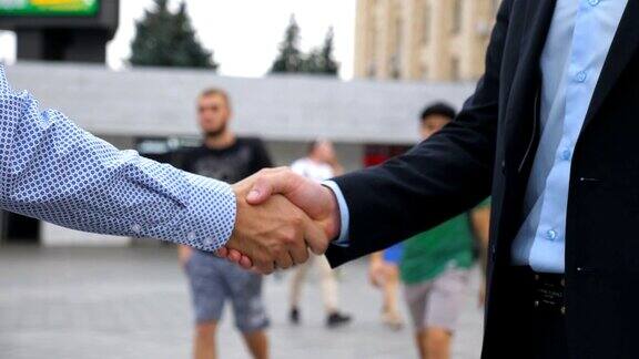 在城市环境中两个不认识的商人相互问候业务握手户外伙伴们在外面握手同事们在城市的背景下见面握手特写慢动作