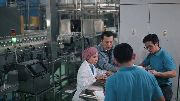 亚洲工厂经理每天在饮水厂生产线与生产线工人开会讨论生产进度