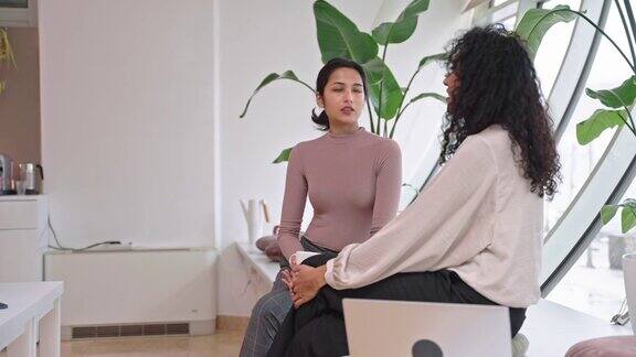 20多岁的印度女性在会议间隙与西班牙裔中年女性同事交谈