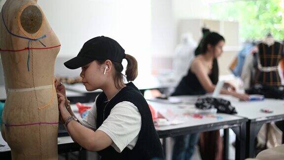 服装设计专业里的亚洲华人在课堂上专心研究他们的时装设计
