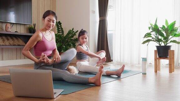 在笔记本电脑视频电话上的虚拟瑜伽课让亚洲母亲和女儿一起健康和幸福