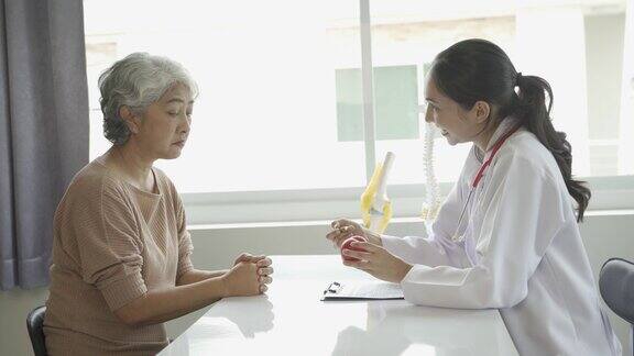 女医生会诊老年病人并开药在门诊坐诊骨关节炎专科女医生看老年人的病史和谈话给出建议