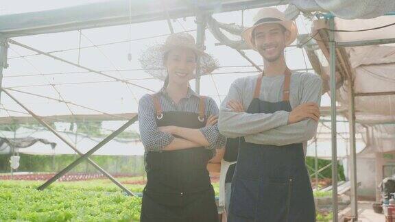 亚洲农民夫妇在蔬菜水培农场工作的肖像有吸引力的青年男女农学家感到自豪和自信的工作后在温室与幸福然后看着相机