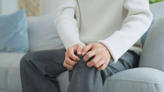 亚洲老年男子腿部受伤感到疼痛和痛苦有魅力的成熟男性病人坐在家里客厅的沙发上膝盖有问题医疗保健保险概念