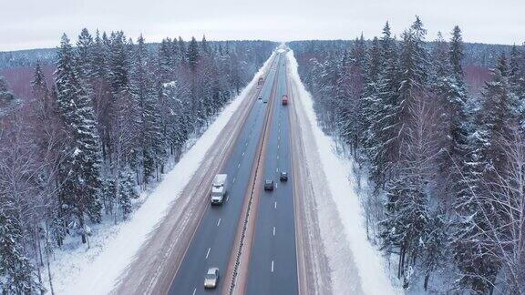 一辆黑白相间的小汽车和一辆卡车行驶在白雪覆盖的森林中央的道路上