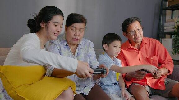亚洲青少年和男孩教如何在家里的客厅玩电子游戏的老年人