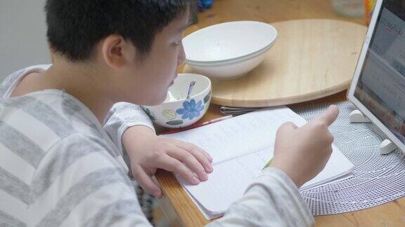 亚洲男孩在家里的餐桌上与老师和朋友一起使用数码平板电脑在线学习这是一种新的正常的生活方式概念