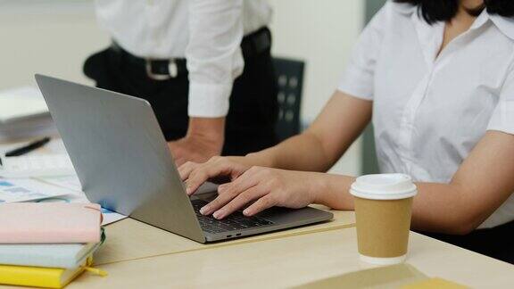 年轻的女办公室职员用手在笔记本电脑上打字在会议上与同事一起做新项目