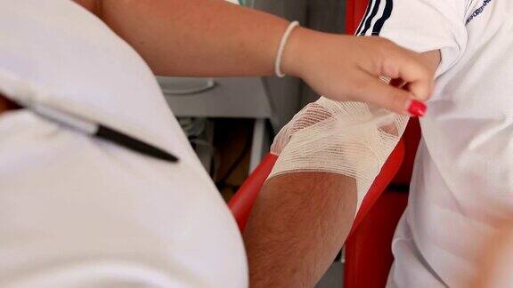 献血者献血后护士包扎献血者的手好事为身体献血的好处接受输血者的手献血者在医疗诊所献血的特写