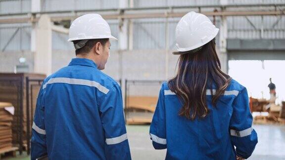 年轻的成年亚洲男人女人工程师工人一起在工厂仓库工作讨论说话散步使用数码平板电脑团队沟通物流行业业务工业工作人员