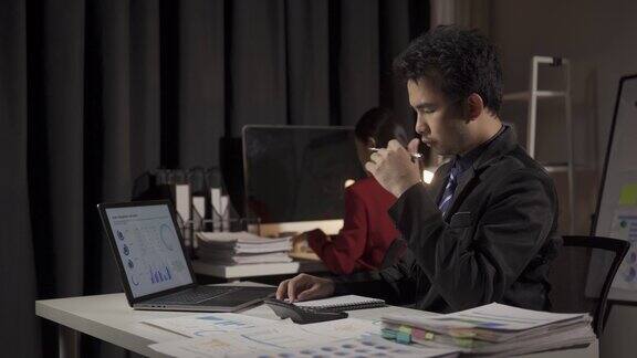 年轻的亚洲商人在办公室里用笔记本电脑和财务文件工作的男人和女人