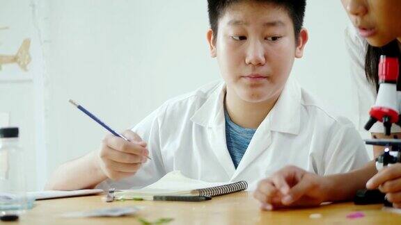 亚洲小学生穿着实验服一起在科学课上使用显微镜教育理念