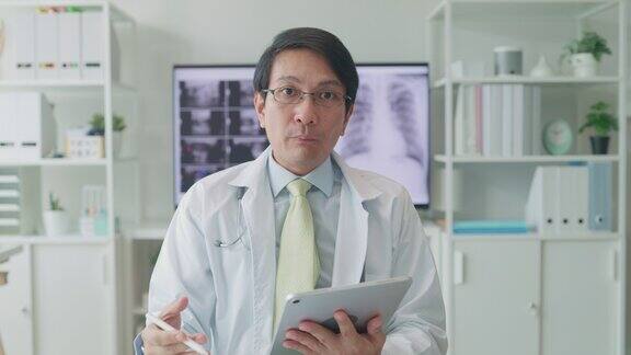 成年亚洲男医生在医院里给病人咨询时看着摄像机视频呼叫医疗结果医疗保健