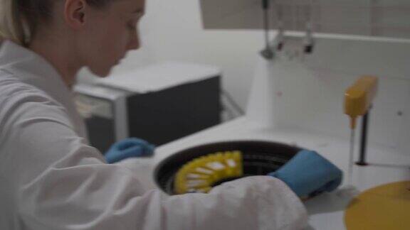 穿着制服的实验室技术人员将血液样本放入用于分析生物液体的自动机器人机器、用于检测样本的临床化学分析仪和医学实验室设备中