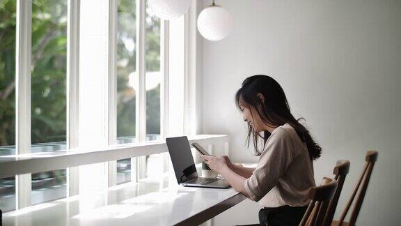 一个亚洲女人在咖啡馆用手提电脑打电话