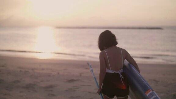 一个年轻女子拿着冲浪板走向海滩