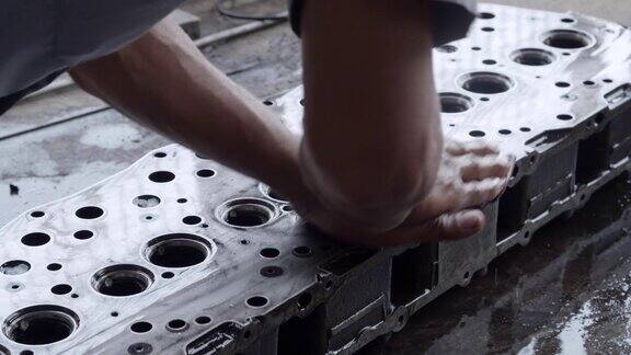 亚洲工人在清洗和抛光汽缸头时用砂纸和润滑油维护发动机