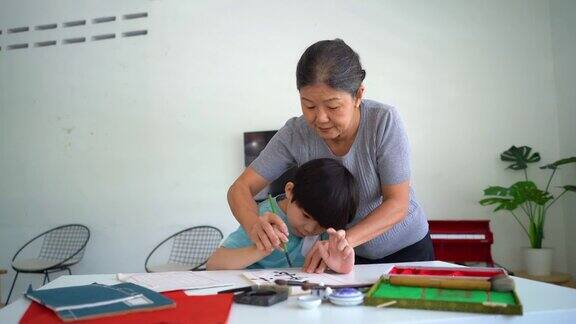 亚洲男孩向他的祖母学习中国书法