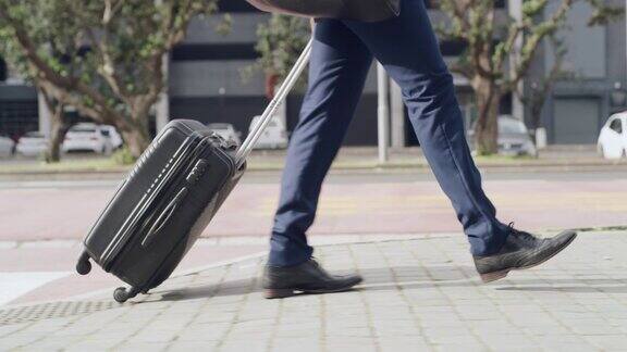 商务旅行商人走在城市的街道上提着一个手提箱去机场现代的管理人员带着行李在赶商务航班的路上