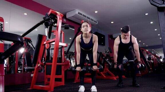 年轻的亚洲肌肉夫妇举起下蹲哑铃在健身房生活方式运动和健身概念