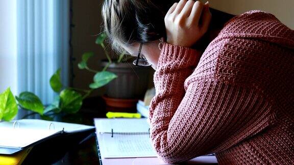 年轻女子一边写笔记一边学习