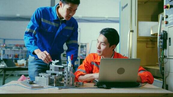 男亚洲工程师专业人员站在工厂的机器旁边讨论两个亚洲同事头脑风暴解释和解决机器的过程